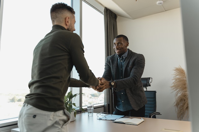 two people standing shaking hands